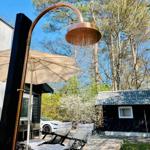 Außendusche mit Dach und Liegestühlen auf Holzterrasse im Garten