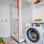 Apartment with shower, washing machine, and storage options.