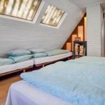 Room with sloped ceiling, two beds, and two skylights with textile glass.