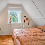 Bedroom with sloped ceiling, window, bed, and hardwood floor.