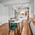 Dining area with white table, green chairs, and hardwood floor. Windowsill with candles and lamp.
