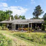 House with terrace and garden, surrounded by trees and flowers.