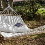Hammock with cushions and book between trees outdoors
