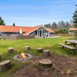 House with garden, fire pit, and picnic table. Red roof ridge and wooden fence.