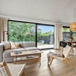 Living and dining area with sofa, table and chairs. Large windows with view of garden.