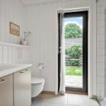 Bathroom with sink, toilet, and shower. Doorway to terrace with garden view.