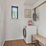 Room with washing machine, bench, and window. Walls with wood paneling and hooks.