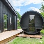 Black wooden cabin with shower and round sauna in the garden