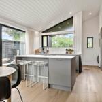 Modern kitchen with island, windows, and wooden floor.