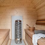 Sauna with wooden bench, stone heater, and towels.