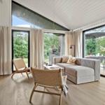 Living room with sofa, chairs, and large windows to the terrace.