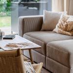 Living area with sofa, table, and chair. Garden visible outside.