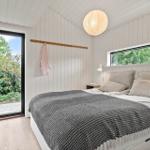 Bedroom with bed, windows, and door to garden. Wooden walls and ceiling.
