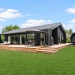Modern villa with wooden terrace, seating, and round sauna in the garden.