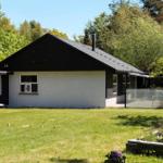 A house with a black roof and white facade. Front yard with grass and flowers.