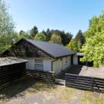 A white house with a black roof and wooden fence in the greenery.