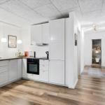 Entryway with mirror cabinet, coffee machine, and wooden floor.