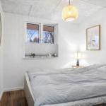 Bedroom with bed, window, and quilt. Wooden floor and lamp.