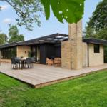Modern villa with terrace, grill area, and garden. Wooden terrace with seating.