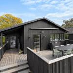 Black wooden house with terrace and outdoor seating area.