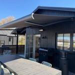 Deck with table, chairs, and grill under a sun shade.
