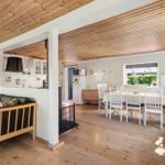 Living and dining area with wooden ceiling, sofa, dining table, and kitchen area.