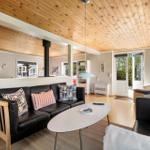 Living room with black sofas, wooden ceiling, and view to the terrace.