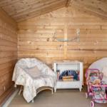 Wood-paneled room with two chairs, bookshelf, and baby stroller.