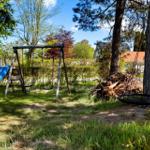 Backyard with playground, slide, and swing under trees.