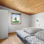 Bedroom with double bed, wooden ceiling, and window. Wall lamp and wardrobe are present.
