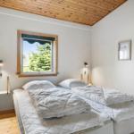 Bedroom with double bed, wooden ceiling, and window with view of trees.
