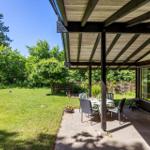 Patio with table and chairs, grill, and view of green lawn.