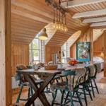 Dining area with wooden table, green chairs with fur trim under wooden ceiling.