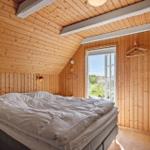 Bedroom with wooden walls, bed, and window with view outside.