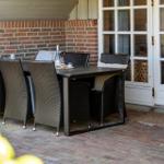 Patio with dining table and chairs in front of brick wall and white doors.