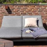 Outdoor terrace with gray lounge sofa, pillow, blanket, and table.