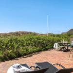 Terrace with loungers, table, and seating. Greenery and sand dunes in the background.