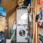 Washing machine and dryer in a tool room with shelves and tool wall.