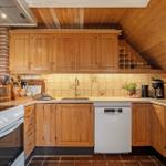 Kitchen with wooden cabinets, tile backsplash, and modern appliances under a sloped wooden ceiling.