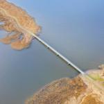 Bridge spans water between two shorelines with vegetation.