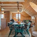 Dining room with wooden ceiling, large table, and green chairs. Wall map of Denmark.