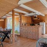 Kitchen with brick wall, dining area, and wood-burning stove under wooden ceiling.