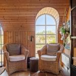 Two woven chairs stand under arched windows with wood paneling.