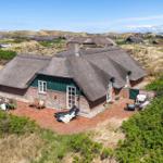 Thatched-roof cottage with terrace and garden. View of dune landscape.