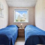 Two beds with blue covers, wooden walls, window with view of trees.