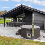 Modern wooden cabin with terrace, grill, and outdoor hot tub.