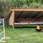 Wooden structure with mattresses, fire pit, and game equipment in the garden.