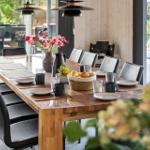 Long wooden table with chairs, flowers, and fruit in dining room.