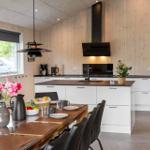 Modern kitchen with dining area, wood paneling, and black appliances.