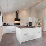 Kitchen with white cabinets, dark worktop, and wood paneling.